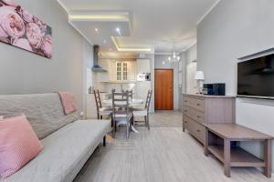 a living room with a couch and a table and a kitchen at Grand Apartments - Neptun Park. in Gdańsk