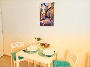 een witte tafel met stoelen en een schilderij aan de muur bij @ Home in Veliko Tŭrnovo