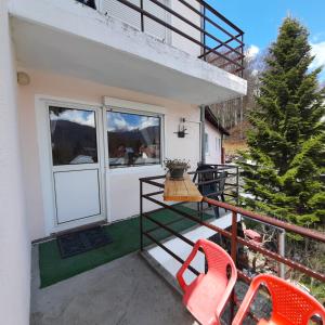 ein Balkon eines Hauses mit zwei orangefarbenen Stühlen in der Unterkunft Apartamente Casa Cristina in Pensiune la 400m de Pârtia de ski in Buşteni