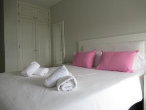 a white bed with pink pillows and towels on it at La Buena Vida, by Comfortable Luxury in Corralejo