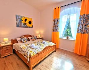 a bedroom with a bed and a window with orange curtains at Pension Haus Anna in Kurort Altenberg