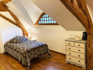 a bedroom with a bed and a dresser with a window at Le Moulin de Pasnel in Monteaux