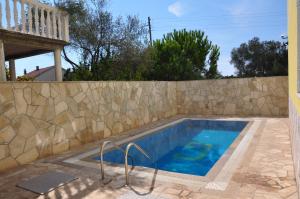 a swimming pool next to a stone fence at Apartments Villa-G Lustica in Tivat