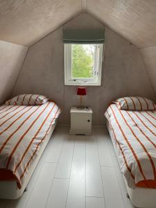 a small room with two beds and a window at De Vuurdoorn in Bergen