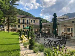 a patio with tables and umbrellas in front of a building at Hotel Versay in Băile Herculane