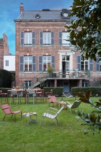 un groupe de chaises et de tables devant un bâtiment dans l'établissement O DELA DE L'O, LE 64 - maison d'hôtes de charme entre Côte d'Albâtre et Baie de Somme, à Eu