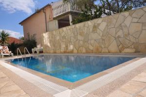 a swimming pool in front of a stone wall at Apartments Villa-G Lustica in Tivat