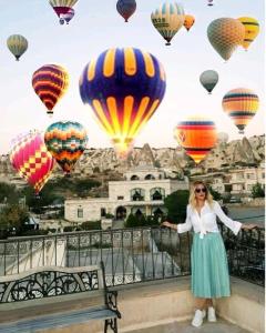 a woman standing next to a bench with hot air balloons at Kemal's Guest House in Goreme