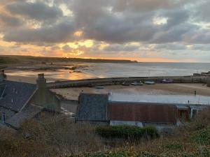 a sunset over a beach with boats in the water at Pear Tree Cottage in Cullen