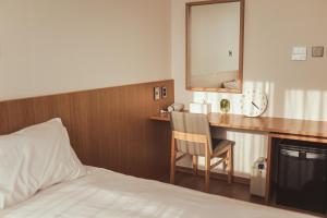 ソギポにあるKenny Stay Jeju Mosulpoのベッド、鏡付きのデスクが備わるホテルルームです。