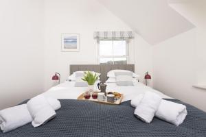 a white bedroom with a bed with a tray of food on it at Harbour Master's House in Portreath