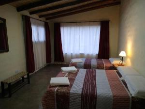 2 Betten in einem Zimmer mit roten Vorhängen in der Unterkunft Pirca del Abuelo II in Purmamarca