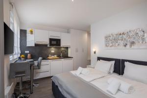 a white bedroom with a bed and a kitchen at Luxury Studios & Room Five in Split