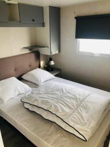 - un grand lit blanc dans une chambre avec fenêtre dans l'établissement Mobil-home 4 personnes 400m de la mer, à Berck-sur-Mer