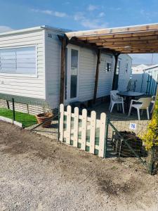 a white fence in front of a house with a table at Mobil-home 4 personnes 400m de la mer in Berck-sur-Mer