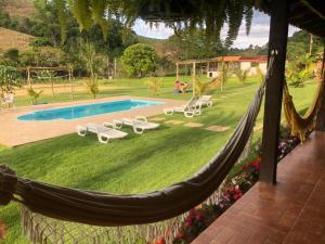 a hammock in a yard with a swimming pool at Paraíso Capitólio "A Pousada da Dona Perpetua" in Capitólio