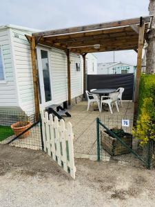 eine Terrasse mit einem Tisch, einem Zaun und einem Haus in der Unterkunft Mobil-home 4 personnes 400m de la mer in Berck-sur-Mer
