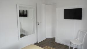 a white room with a chair and a television on a wall at La Maison Cent 5 avec parking privé in Saint-Valery-sur-Somme