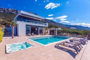 een villa met een zwembad en een huis bij Luxurius Villa Aria with heated 45sqm pool, jacuzzi and seaview in Kaštela