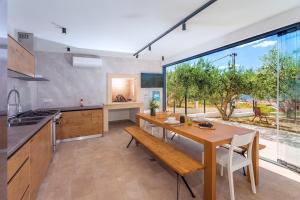 een keuken met een houten tafel en een groot raam bij Luxurius Villa Aria with heated 45sqm pool, jacuzzi and seaview in Kaštela