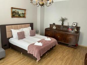 ein Schlafzimmer mit einem Bett und einer Kommode mit zwei Handtüchern in der Unterkunft APARTMENT SILESIAN STADIUM and PARK in Chorzów