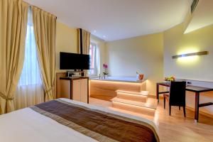 a hotel room with a bed and a desk and a television at Hotel Master in Brescia