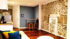 a living room with a stone wall and a kitchen at Cordeliers Jordans Flat City centre historique in Dijon