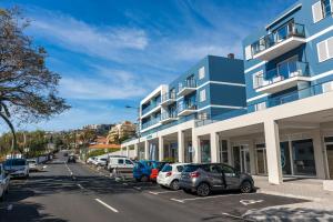 ein blaues Gebäude mit Autos auf einem Parkplatz in der Unterkunft Sun and Sea II in Caniço