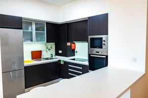 eine Küche mit schwarzen Schränken, einer Mikrowelle und einem Kühlschrank in der Unterkunft Sun and Sea II in Caniço