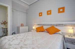 a bedroom with a large bed with two orange pillows at 13 Avenida Andalucía in Ronda