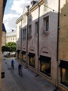 two people riding bikes down a street next to a building at Cordeliers Jordans Flat City centre historique in Dijon