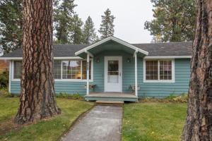 una casa blu con una porta bianca tra due alberi di Pine Street Cottage a Sisters
