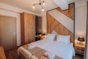een slaapkamer met een groot wit bed met een houten hoofdeinde bij Pearl Apartments in Ohrid