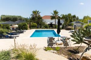 a pool with chairs and umbrellas in a resort at Casa Verdazul in Tavira