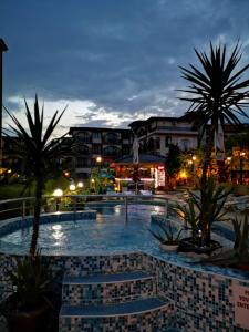 uma grande piscina com palmeiras e edifícios em Family Hotel Rainbow em Sveti Vlas
