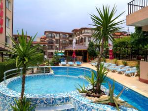 uma grande piscina com palmeiras e cadeiras em Family Hotel Rainbow em Sveti Vlas