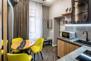 a kitchen with yellow chairs and a table and a sink at Alfa Apartments Kulisha 12 in Lviv +24 photos