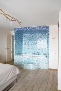 a bathroom with a blue tile wall with a tub at Vitamine Zee in IJmuiden