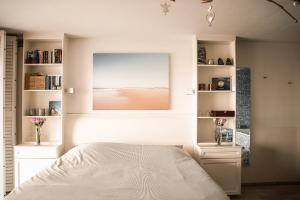 a white bedroom with a bed and a window at Vitamine Zee in IJmuiden