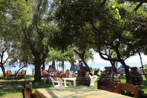 a group of people sitting at tables near the water at Eleni Rooms Develiki in Ierissos