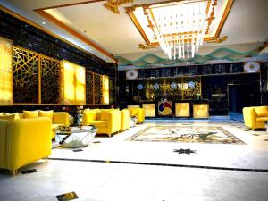 a lobby with yellow chairs and a chandelier at Asian Hotel in Duqm