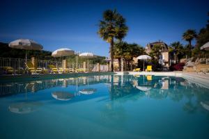 una gran piscina de agua azul con sillas y sombrillas en Les Magnolias holiday homes en Lalinde