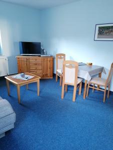 a living room with a table and chairs and a tv at Ferienwohnung 4, Waldesruh Dierhagen in Dierhagen