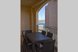 a table and chairs on a balcony with a view of the ocean at Sunny Apartment in Tas-Sellum Mellieha, Malta. in Għajn Żejtuna