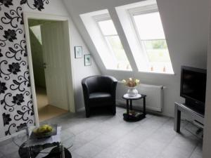 een woonkamer met een stoel en een spiegel bij Fewo Lüheblick im Haus Lühegarten in Grünendeich