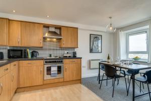 a kitchen with wooden cabinets and a table with chairs at Chic and Bright Apartment Near the Water in Plymouth