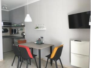 a small kitchen with a table with chairs and a refrigerator at Balatonlelle Apartmanház in Balatonlelle