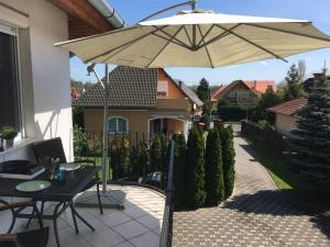 a patio with a table and an umbrella at Balatonlelle Apartmanház in Balatonlelle