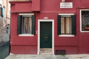 um edifício vermelho com uma porta verde e janelas em BlueYellow home in Cannaregio Air conditioning WiFi em Veneza