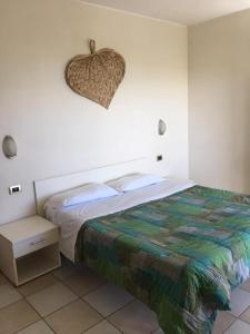 a white bedroom with a bed and a night stand at Elena Club Resort in Silvi Marina